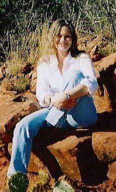 Mary Loomis smiling, sitting on a red rock.